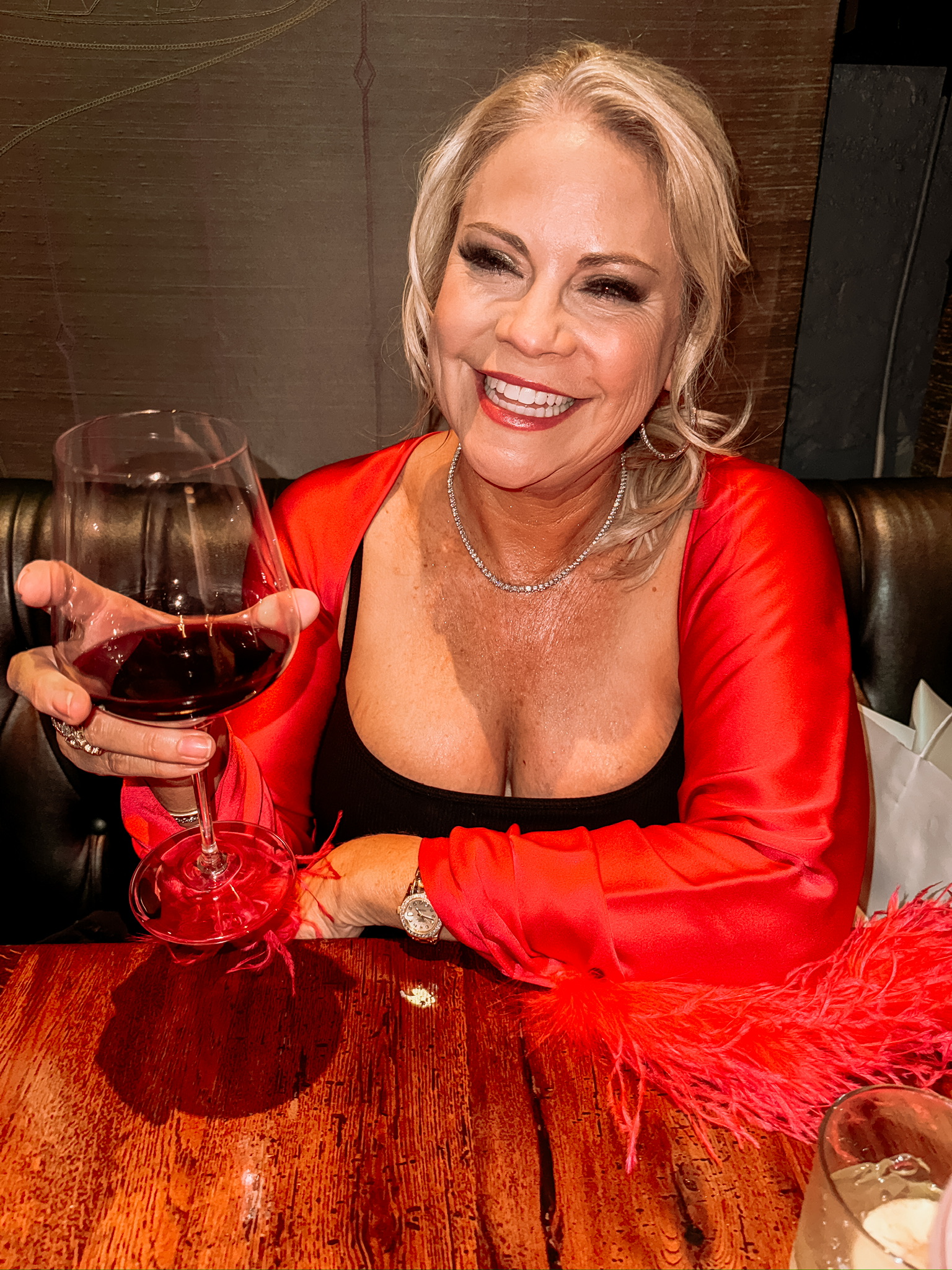 my new york fashion week experience, amy wearing black shapewear  dress with red cape and holding a glass of red wine